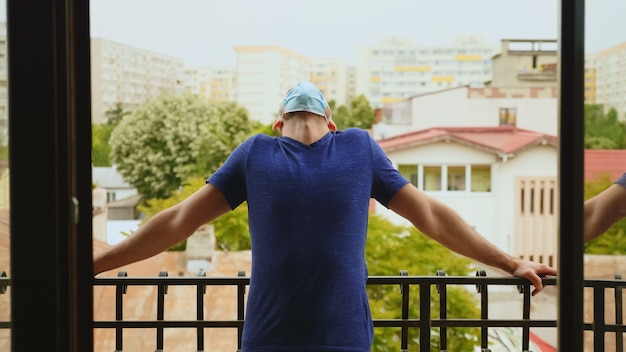 Colpo rivelatore dell'uomo che si rilassa sul balcone durante l'epidemia di covid-19. L'uomo in isolamento.