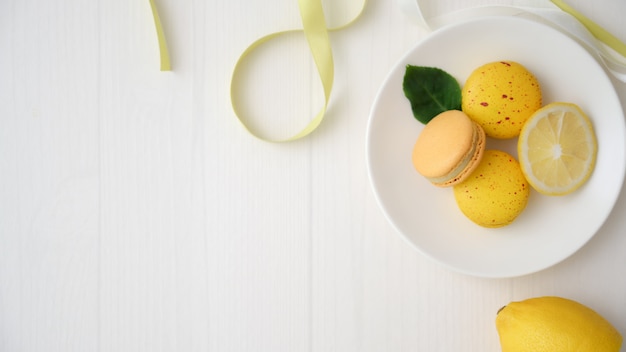 Colpo sopraelevato dei macarons pastelli variopinti sul piatto ceramico bianco sullo scrittorio della plancia