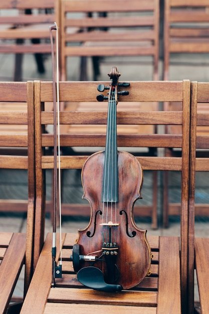 Colpo verticale del violino con l'arco sulla sedia di legno.