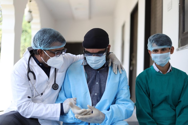 Colpo verticale di tre medici indiani con uniforme medica e maschera sullo sfondo della clinica
