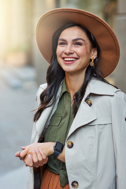 Colpo verticale di una donna attraente e felice che indossa un cappotto grigio e un cappello che guarda da parte e