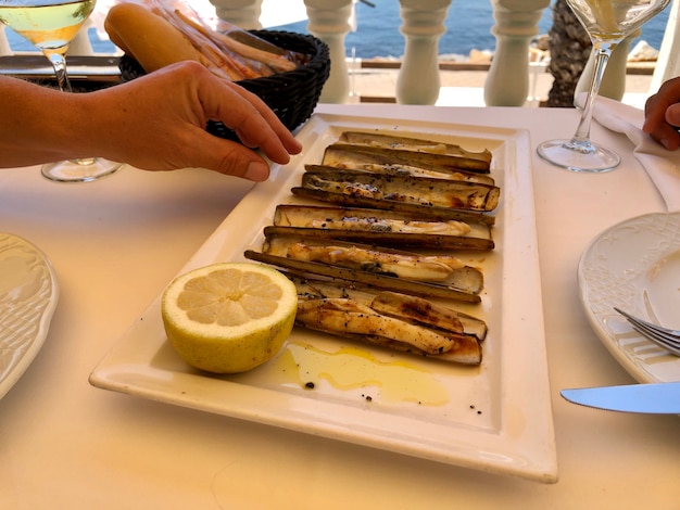 Coltelli di mare tipici mediterranei serviti nello stile di vita del ristorante foto di alta qualità