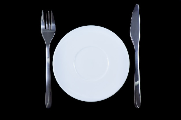 Coltello da tavola, piatto, forchetta su sfondo di vari colori.