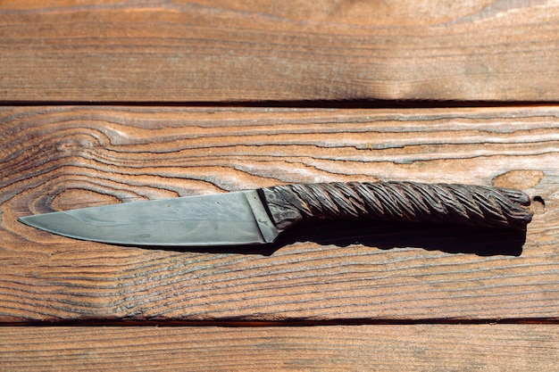 Coltello di un pezzo di metallo fatto della corda della gru del metallo sulla tavola di legno.