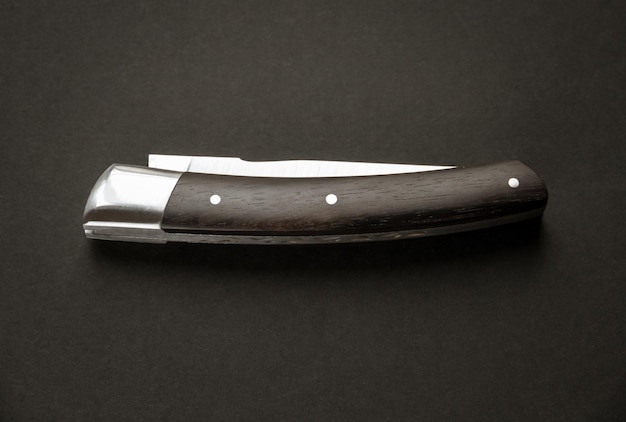 Coltello tascabile tradizionale in legno su sfondo nero