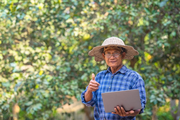 Coltivatore asiatico nel campo con il computer portatile