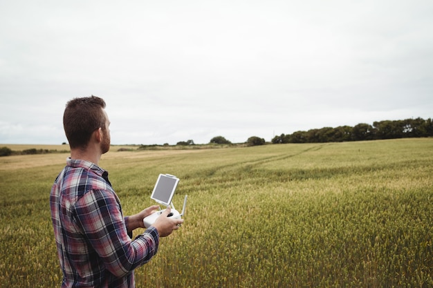 Coltivatore che utilizza dispositivo agricolo mentre esaminando nel campo