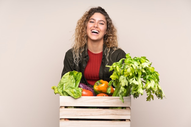 Coltivatore con le verdure appena raccolte in una scatola sulla risata beige della parete