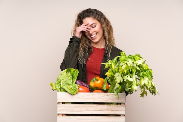 Coltivatore con le verdure appena raccolte in una scatola sulla risata beige