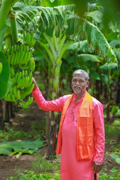 Coltivatore indiano felice che tiene in mano banano crudo