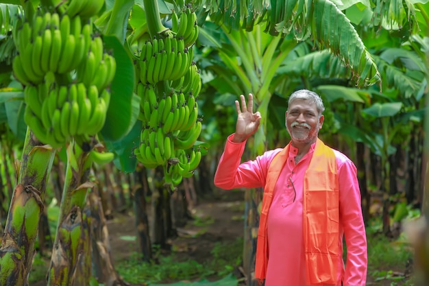 Coltivatore indiano felice che tiene in mano banano crudo