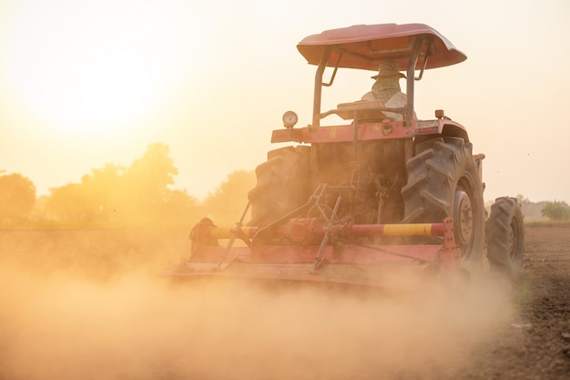 Coltivatore tailandese sul grande trattore nella terra per preparare il terreno