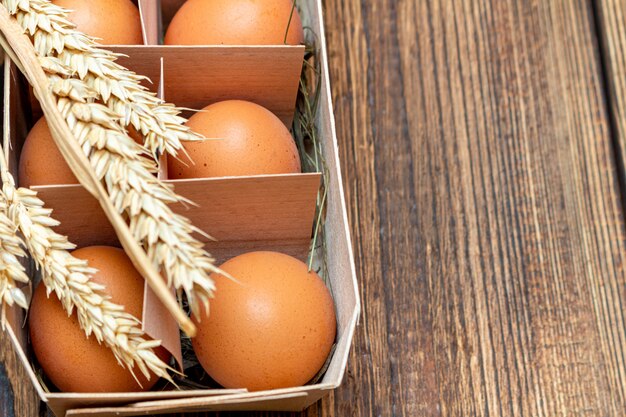 Coltivi le uova marroni con paglia in scatola di legno di betulla con lo spazio della copia.