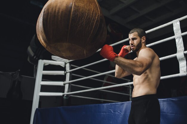 Combattente che pratica alcuni calci con sacco da boxe kick sacco da boxe su sfondo scuro nero sacco da boxe pesa in palestra k filmati di alta qualità