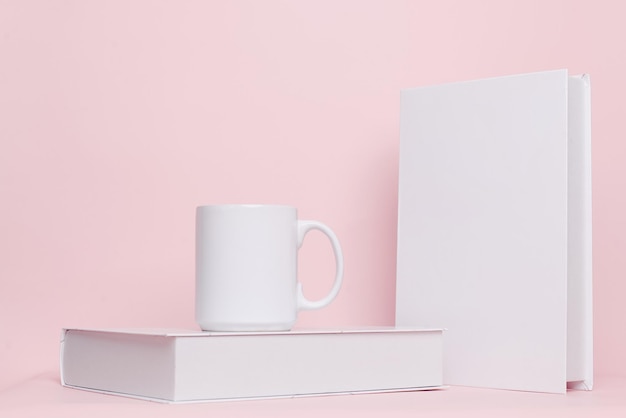 Combinazione di tazza e libro per mock up isolato su sfondo rosa