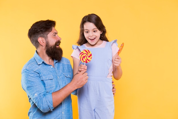 Come accontentare tuo figlio ed evitare problemi Cibo dolce Bambina e papà tengono lecca-lecca Dessert dolce Papà amorevole per figlia Concetto di dolci e dolcetti Dieta zucchero Assistenza sanitaria Dolce vita