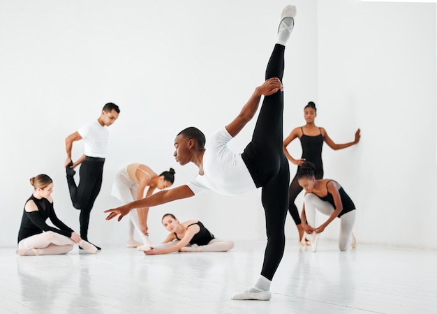 Come ballerino, devi essere flessibile. Colpo a figura intera di un gruppo eterogeneo di studenti di balletto che provano nel loro studio di danza.