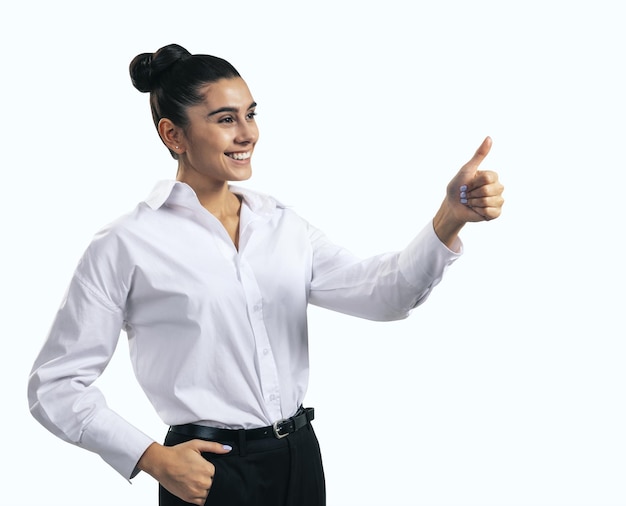 Come il concetto con una giovane donna felice in camicia bianca che tiene i pollici in su su sfondo bianco vicino isolato