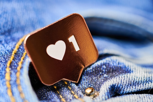 Come il simbolo del cuore. Pulsante come segno, simbolo con cuore e una cifra. Marketing di rete sui social media. Fondo di struttura dei jeans blu.