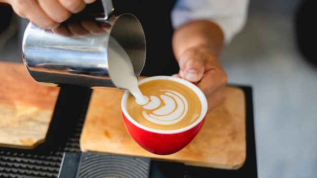 Come rendere il caffè latte art del barista concentrato nel latte e nella tazza di caffè nella caffetteria