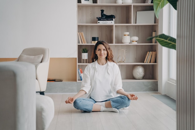 Comfort e serenità Una donna ispanica rilassata sta praticando yoga e meditazione sul pavimento di casa