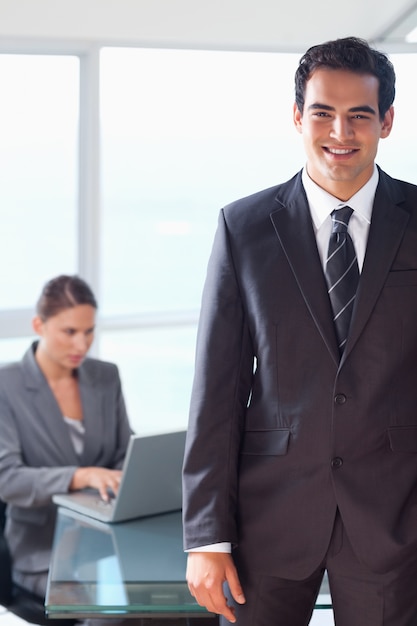 Commerciante sorridente con il collega di lavoro dietro di lui