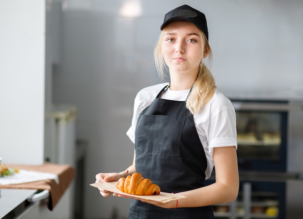 Commessa di giovane bella ragazza in un caffè con pasticcini e una panetteria