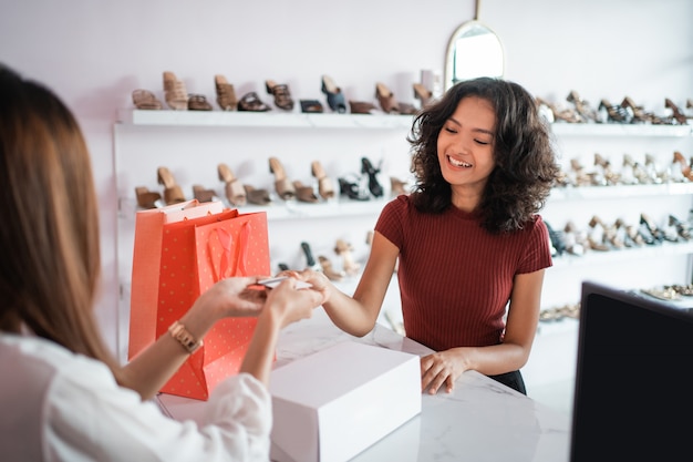 Commesso asiatico della donna con i contenitori di scarpe al deposito