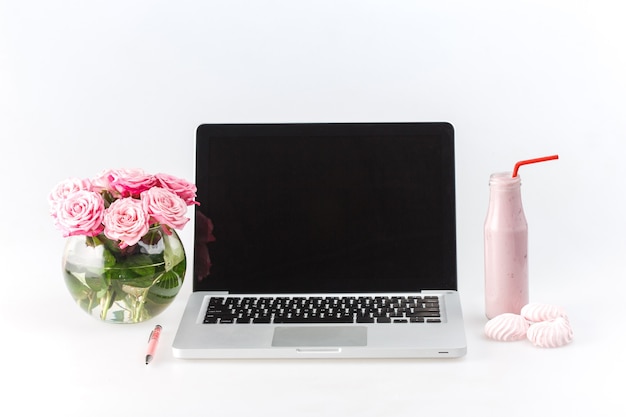 Comodo posto di lavoro femminile con laptop, rose, yogurt su bianco