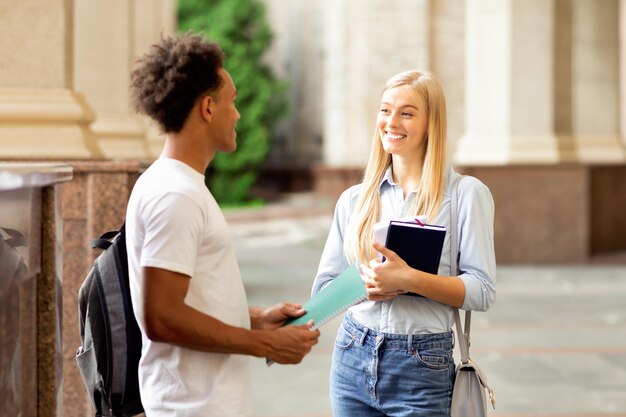 Compagni di classe che parlano nel campus universitario che fanno una pausa tra le lezioni che si riposano all'aperto