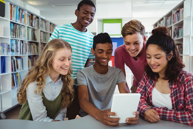 Compagni di classe felici utilizzando la tavoletta digitale in libreria