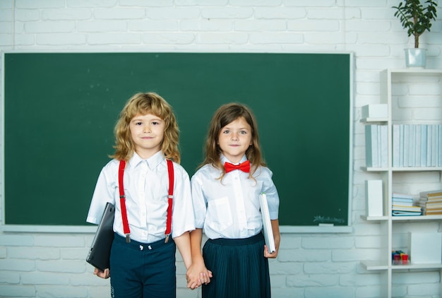 Compagni di scuola due scolari ragazza e ragazzo che si tengono per mano andando a scuola in prima classe