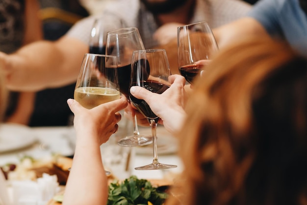 Compagnia di amici che si divertono a cena in un ristorante Sul tavolo una varietà di piatti dello chef Hanno cliccato i loro bicchieri di vino Fotografia concettuale Vista dall'alto