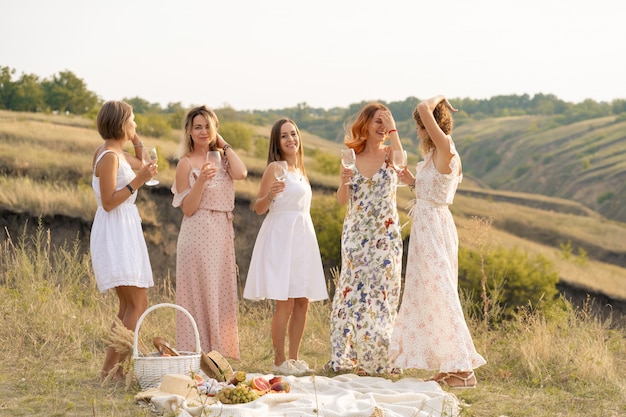 compagnia di bellissime amiche che si divertono e si godono un picnic estivo verde, ballando e bevendo alcolici. Concetto di persone.