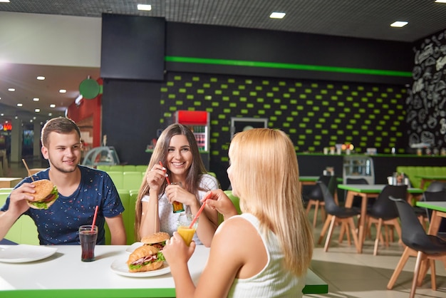 Compagnia seduta al bar e mangiando deliziosi fast food?