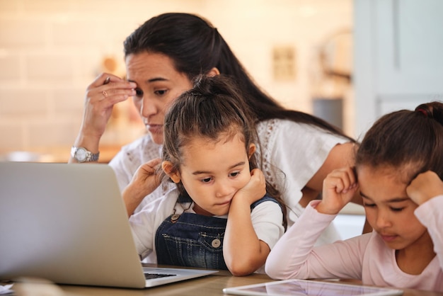 Compartimentare il tempo per sé e per i suoi figli. Inquadratura di una giovane madre che aiuta le sue figlie a fare i compiti.