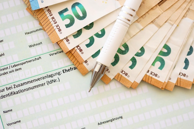 Compilazione del modulo fiscale tedesco con penna e banconote in euro per chiudere il periodo di pagamento delle imposte