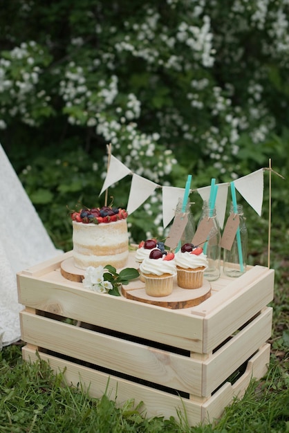 Compleanno estivo, decorazione in giardino. Torte Cupcake con frutti di bosco su una scatola di legno.