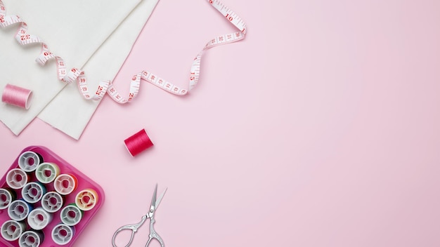 Composition with various threads and sewing accessories on pink background Top view copy space