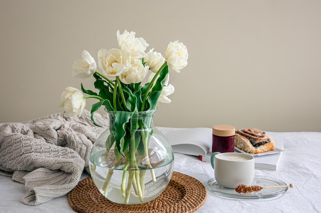 Composizione accogliente con un bouquet di fiori caffè e un panino a letto