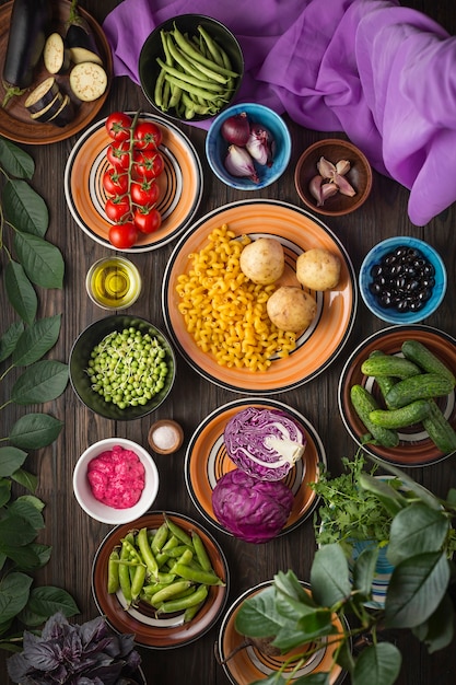 Composizione alimentare. Alimenti biologici, verdure e cereali in ciotole di argilla multicolore su un tavolo di legno.