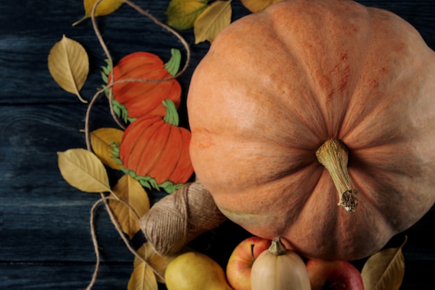 Composizione autunnale con zucca e frutti autunnali con mele e pere su un tavolo blu scuro e su uno sfondo nero