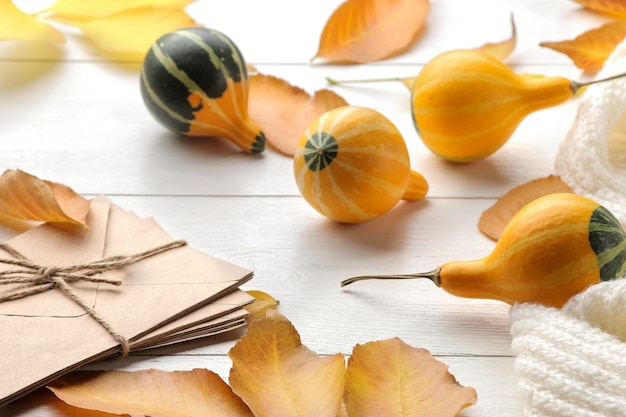 Composizione autunnale con zucche decorative e foglie gialle e una calda sciarpa. tempo d'autunno. su un tavolo di legno bianco.