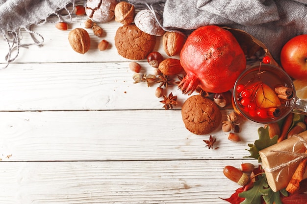 Composizione autunnale di foglie di autunno frutti e spezie su un tavolo di legno bianco