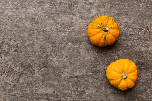 Composizione autunnale di piccole zucche arancioni su sfondo colorato tavolo Autunno Halloween e concetto di ringraziamento Fotografia piatta autunnale Vista dall'alto con spazio di copia