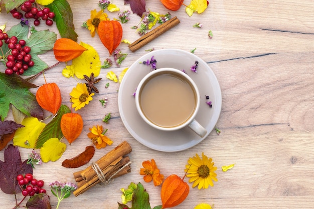 composizione autunnale tazza di caffè su un tavolo con fiori e foglie vista dall'alto immagine di sfondo