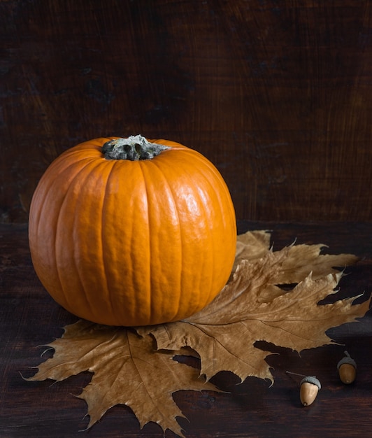 Composizione autunnale Zucca foglie secche ghiande su uno sfondo di legno scuro