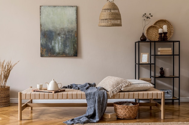 Composizione boho da salotto con chaise longue di design, cuscini, cesti, quadri, decori in rattan naturale ed eleganti accessori personali.