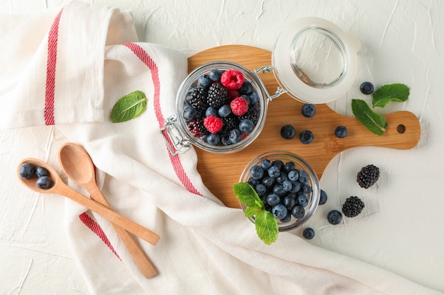 Composizione con accessori da cucina e bacche sullo spazio di cemento bianco