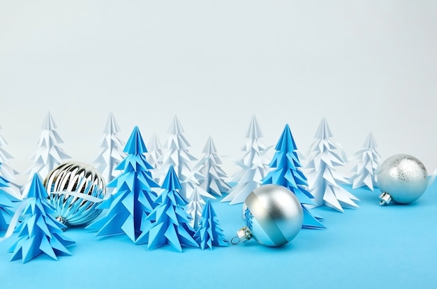 Composizione con alberi di Natale in carta bianca e blu e decorazioni a sfera